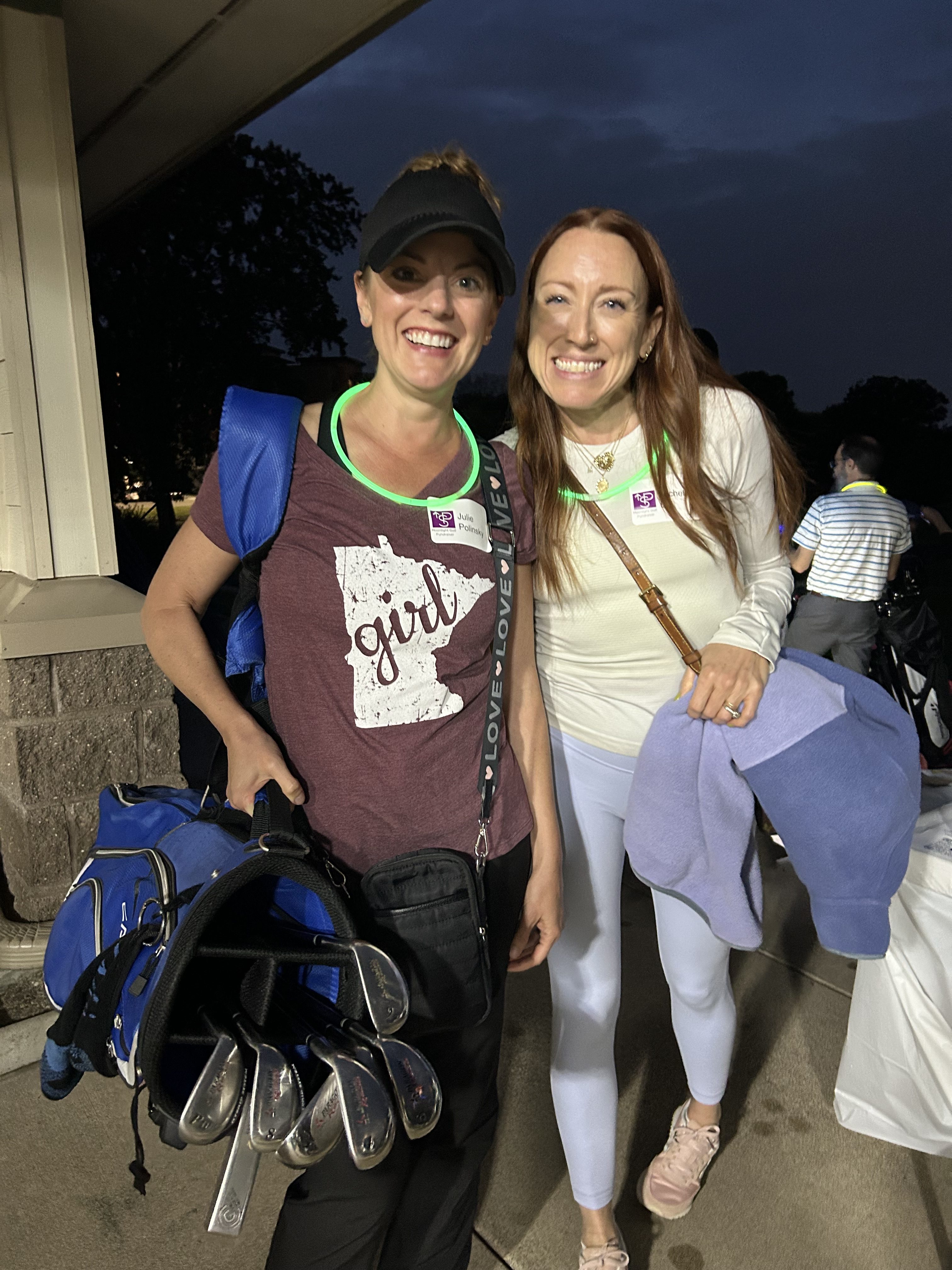 Two women smiling and holding golf bags