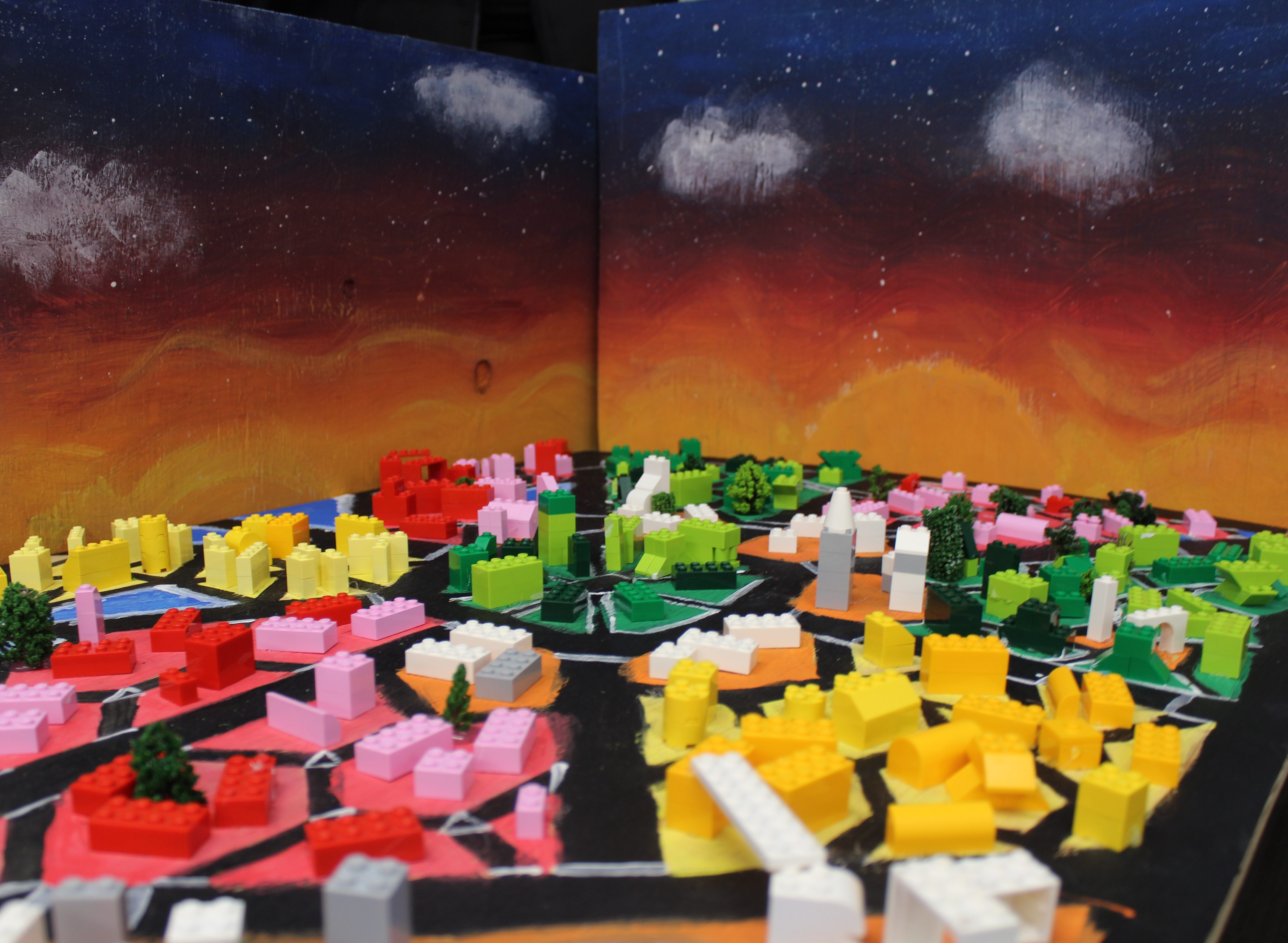 A colorful cityscape model with a starry sunset background.