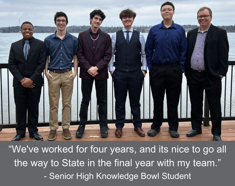 Five students and one adult, dressed formally, stand smiling on a deck by a lake at Knowledge Bowl State.