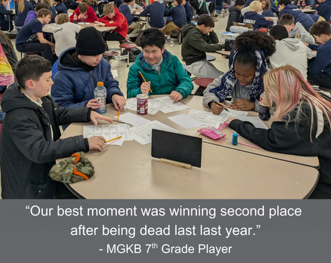 Students sit at a round table, working on the written round at a Knowledge Bowl meet